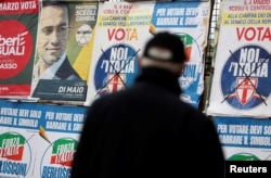 A man looks at electoral posters in Pomigliano D'Arco, near Naples, Italy, Feb. 21, 2018.