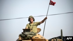 Tentara Turki mengendarai tank ketika akan memasuki kota Jarablus, Suriah dekat perbatasan Turki (25/8) lalu. 