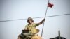 FILE - A soldier gestures as Turkish Army tanks drive to the Syrian-Turkish border town of Jarabulus, Aug. 25, 2016.