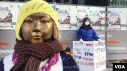 University student Kim So-min, 21, stands in protest outside the Japanese Embassy in Seoul near a bronze statue of a young Korean girl, a reminder of Japan's World War II comfort women. (B. Harrison/VOA ) 