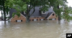 A home is shown as floodwaters from Tropical Storm Harvey rise, Aug. 28, 2017, in Spring, Texas.