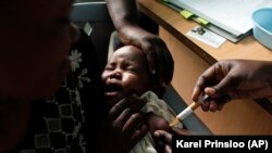 아프리카 케냐 콤베와에서 엄마 품에 안긴 아기가 말라리아 백신 테스트를 받고 있다. (자료사진)