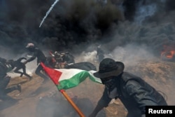 Palestinian demonstrators run for cover from Israeli fire and tear gas during a protest against U.S. embassy move to Jerusalem and ahead of the 70th anniversary of Nakba, at the Israel-Gaza border in the southern Gaza Strip, May 14, 2018.