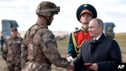 El presidente ruso, Vladimir Putin, a la derecha, premia a un militar chino en el campo de entrenamiento "Tsugol", a unos 250 kilómetros (156 millas) al sureste de la ciudad de Chita durante los ejercicios militares Vostok 2018 en Siberia Oriental, Rusia, el jueves, 13 de septiembre 2018. 