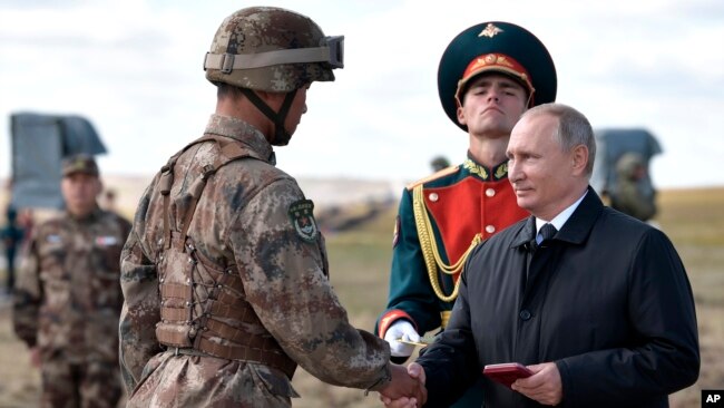 俄罗斯总统普京（右）在中俄边界附近举行的“东方-2018”战略军演后给一名中国军人颁发勋章。（2018年9月13日）