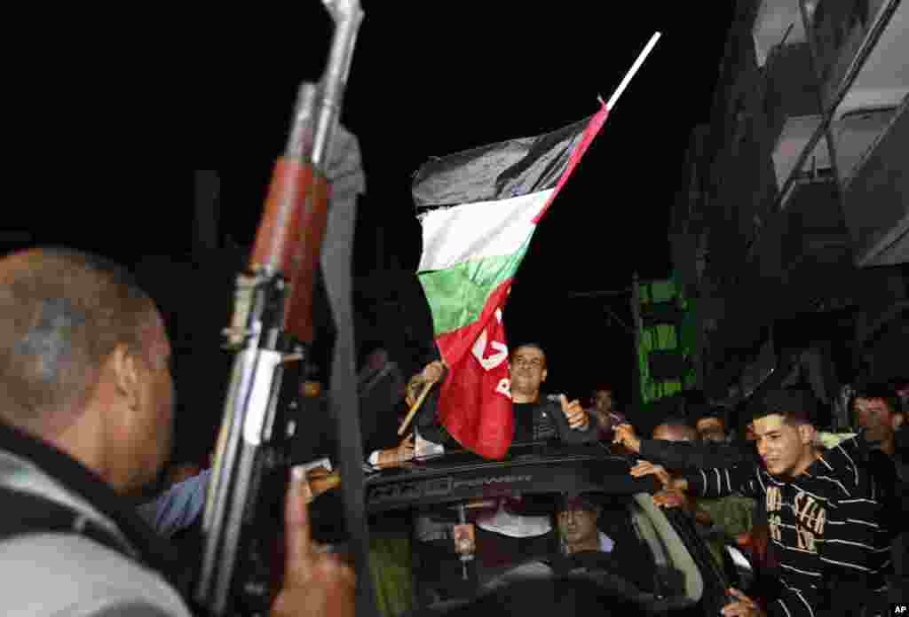 A Palestinian man fires a gun while others gather around a released Palestinian prisoner, Omar Masoud, upon his arrival at his family house in Shati Refugee Camp, Oct. 30, 2013.