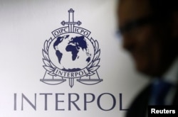 FILE - A man passes an Interpol logo.