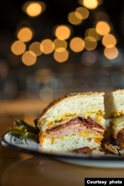 The muffuletta is a sandwich made by Sicilian immigrants in New Orleans.  It was supposedly made in 1906 and consists of olive salad and a mix of Italian meat and cheese on a round Sicilian sesame bread.  (Courtesy photo of Cochon Restaurant.)