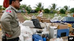 A Cambodian police officer stands next to equipment used to make various drugs, which were seized in raids earlier this year in eastern and southern Cambodia, on the outskirt of Phnom Penh, file photo. 