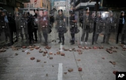 FILE - Riot police stand guard as rioters set fires and throw bricks in Mong Kok district of Hong Kong, Feb. 9, 2016.