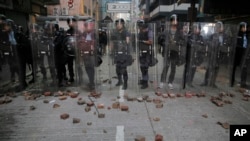 FILE - Riot police stand guard as rioters set fires and throw bricks in Mong Kok district of Hong Kong, Feb. 9, 2016.