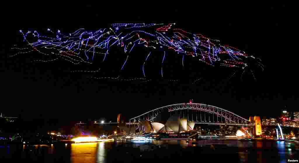 An aerial performance featuring 100 illuminated drones fly above the Sydney Harbour Bridge and Opera House during the Vivid Sydney light festival in Sydney, Australia.