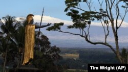 Snow on Mauna Kea is seen Friday Jan. 31, 2014, behind a statue of the Hawaiian King Kamehameha in Hilo, Hawaii. (AP Photo/Tim Wright)