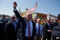 Republican presidential candidate Donald Trump waves as he walks with vice presidential candidate Gov. Mike Pence, R-Ind., during a visit to the170th Canfield Fair, Sept. 5, 2016, in Canfield, Ohio.