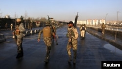 Afghan security forces walk at the site of a suicide attack in Kabul, Afghanistan, Feb. 27, 2016. 