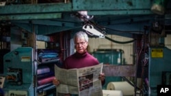 FILE - Reed Anfinson, publisher of The Swift County Monitor-News, holds the latest edition as he stands for a portrait at Quinco Press in Lowry, Minn., Nov. 30, 2021.