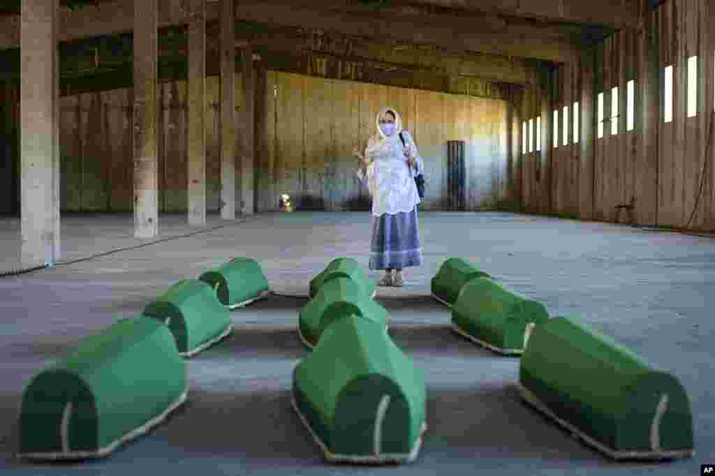 A woman prays next to coffins at the former U.N. base in Potocari, Bosnia. Nine newly found men and boys will be laid to rest when Bosnians commemorate 25 years since Srebrenica was overrun by Bosnian Serb forces, in Europe&#39;s worst post-WWII massacre.