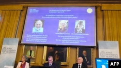 Members of the Nobel Committee for Physics sit in front of a screen displaying portraits of Arthur Ashkin of the United States, Gerard Mourou of France and Donna Strickland of Canada during the announcement of the winners of the 2018 Nobel Prize in Physic