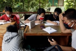 Dimas Anwar Saputra, siswi SMP berusia 15 tahun, mengenakan masker pelindung berwarna merah, belajar bersama siswa lain menggunakan akses internet wifi gratis.(Foto: REUTERS/Willy Kurniawan)