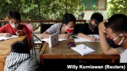 Dimas Anwar Saputra, siswi SMP berusia 15 tahun, mengenakan masker pelindung berwarna merah, belajar bersama siswa lain menggunakan akses internet wifi gratis yang mereka dapatkan dengan menukar sampah plastik, Jakarta, 9 September 2020. (Foto: REUTERS/Wi