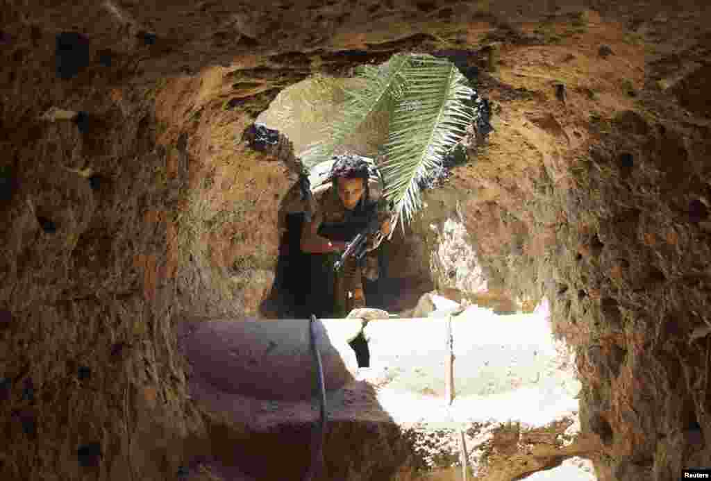A Free Syrian Army fighter moves through a tunnel to take cover from snipers loyal to Syria&#39;s President Bashar al-Assad in Deir al-Zor, July 14, 2013. 