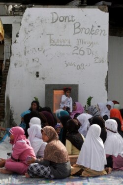 Perempuan Aceh menghadiri sholat massal untuk para korban tsunami di Banda Aceh 26 Desember 2009. Korban berkumpul di masjid atau rumah sekitar untuk mengenang mereka yang terbunuh oleh dinding air setinggi 30 meter yang dipicu oleh gempa bawah laut lepas