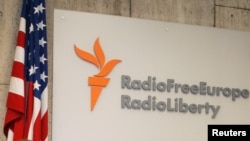 ປ້າຍ Radio Free Europe/Radio Liberty ຕິດຢູ່ຂ້າງໆ
ທຸງຊາດສະຫະລັດ ທີ່ເປັນຜູ້ໃຫ້ທຶນ ໃນນະຄອນ Prague, Czech Republic, 5 ຕຸລາ 2005.