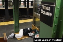 Seorang pria tunawisma tidur di sebuah stasiun kereta api New York sepi karena wabah Covid-19 di New York, 13 April 2020. (Foto: Lucas Jackson/Reuters)