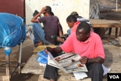 Men read the paper in Westfield, Banjul, Gambia, June 7, 2017. (S.Christensen/VOA)