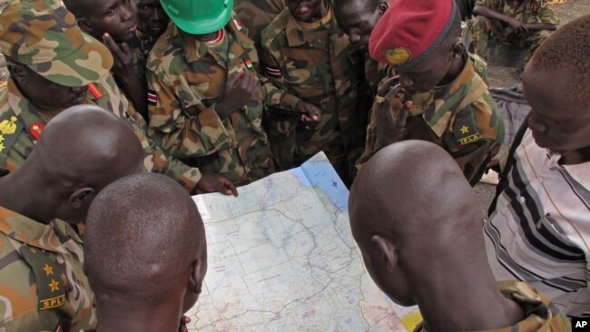 FILE - Soldiers from the Sudan People's Liberation Army examine a map at the front-line position in Pana Kuach, Unity State, South Sudan, May 11, 2012.