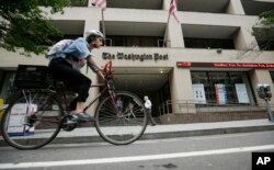 FILE - A bicyclist rides past The Washington Post building, Aug. 6, 2013, in Washington.