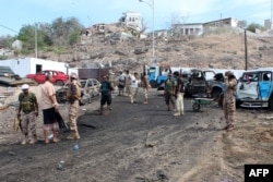 FILE - Yemeni loyalist forces and onlookers gather at the scene of a suicide attack targeting the police chief in the base of the Saudi-backed government in Aden, Yemen, April 28, 2016.