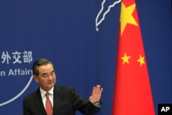 FILE - China's Foreign Minister Wang Yi waves after a press conference for the up-coming BRICS summit, at the Ministry of Foreign Affairs in Beijing, Aug. 30, 2017.