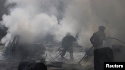 FILE - Civil defense members try to put out a fire at a site hit by what activists said was a barrel bomb dropped by forces loyal to Syria's President Bashar al-Assad in the Qadi Askar neighborhood of Aleppo, March 5, 2015. 