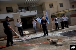 An Israeli man cleans blood stains at the scene of a stabbing attack in Beit Shemesh, central Israel, Oct. 22, 2015. Police say two Palestinians stabbed an Israeli man after attempting to board a bus ferrying children to school.