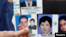 FILE - A nephew of missing person Omaira Montoya, a member of Colombia's rebel group National Liberation Army (ELN) who disappeared in 1977, holds a photograph of her during an event marking the International Day of the Victims of Enforced Disappearances in Medellin, Colombia, Aug. 30, 2016.