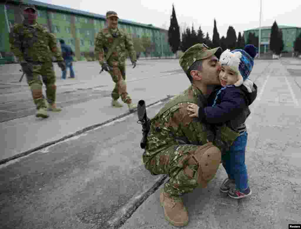 Seorang tentara memeluk anaknya setelah sebuah upacara perpisahan di pangkalan militer Vaziani, di luar Tbilisi, Georgia.