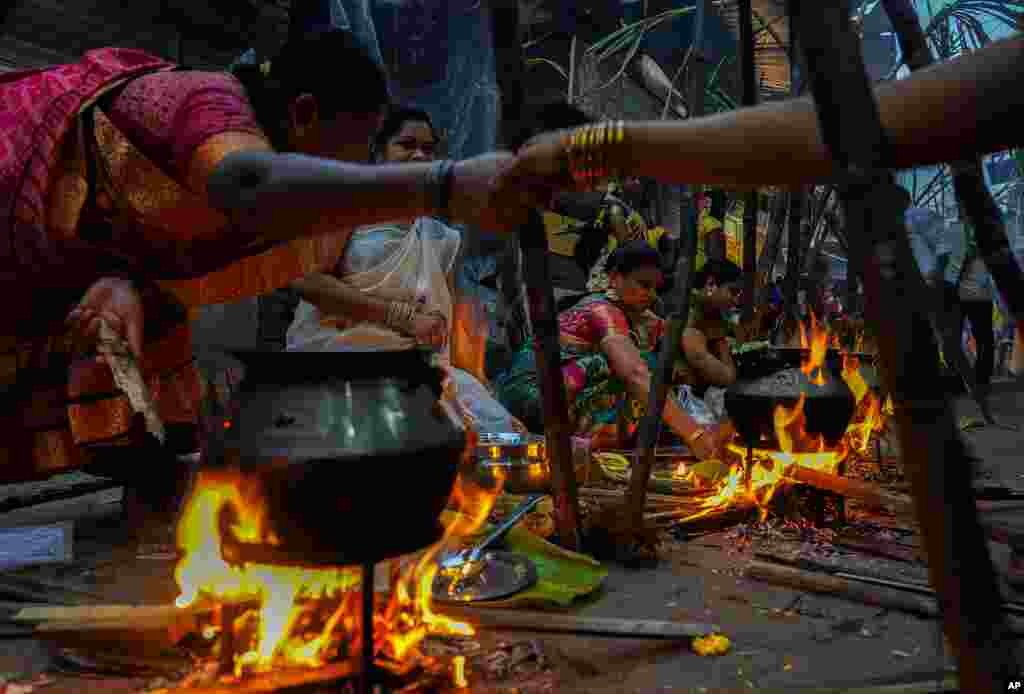 Tamil women greet each other as they cook special food to celebrate the harvest festival of Pongal at Dharavi, one of the Asia&#39;s largest slums, in Mumbai, India.