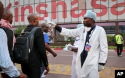 A health worker checks people's temperatures as they disembark a plane at the airport in Kinshasa, Congo, June 2, 2018.