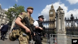  FILE - A member of the army joins police officers on patrol in Westminster, London, May 24, 2017. Britons find armed troops at vital locations as the country's terror threat level remains at "severe" - the second highest on Britain's five-tier scale.