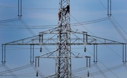 FILE - Workers of the German energy company RWE prepare power supply on a high power pylon in Moers, Germany, April 11, 2011.