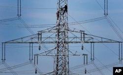FILE - Workers of the German energy company RWE prepare power supply on a high power pylon in Moers, Germany, April 11, 2011.