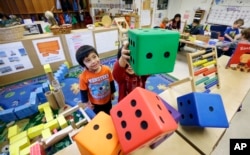 FILE - In this photo taken Friday, Feb. 12, 2016, Daniel O'Donnell, left, looks on as William Hayden sends large blocks flying at the Creative Kids Learning Center, a school that focuses on pre-kindergarten in Seattle. (AP Photo/Elaine Thompson)