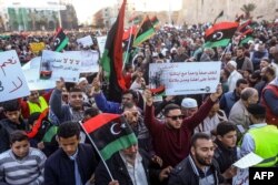 Libyans wave national flags and chant slogans during a demonstration against strongman Khalifa Haftar in Martyrs Square, Tripoli, April 12, 2019.