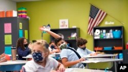 Seorang siswa mengangkat tangannya di kelas di iPrep Academy pada hari pertama sekolah, Senin, 23 Agustus 2021, di Miami. Sekolah-sekolah di Miami-Dade County dibuka Senin dengan prokes ketat dan kewajiban mengenakan masker. (Foto AP/Lynne Sladky).