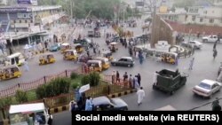 Taliban militants waving a Taliban flag on the back of a pickup truck drive past a crowded street at Pashtunistan Square area in Jalalabad, Afghanistan in this still image taken from social media video uploaded on August 15, 2021. Social media website/via REUTERS THIS IMAGE HAS B