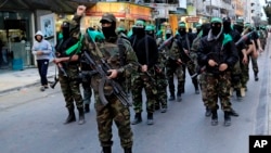 FILE - Palestinian masked militants of Izzedine al-Qassam Brigades, a military wing of Hamas, mark the 11th anniversary of the Israeli assassination of Hamas spiritual leader Sheikh Ahmad Yassin in Gaza, in the northern Gaza Strip. 