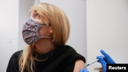 လန်ဒန်မြို့မှာ ကိုဗစ်ကာကွယ်ဆေး အထိုးခံနေတဲ့ အမျိုးသမီးတဦး။ (ဒီဇင်ဘာ ၁၅၊ ၂၀၂၁)