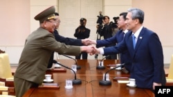 This handout photo from the S. Korean Unification Ministry shows the S. Korean president's national security adviser, Kim Kwan-Jin (R), and Unification Minister Hong Yong-Pyo (2nd R) shaking hands with the N. Korean officials during their meeting, Aug. 22, 2015.
