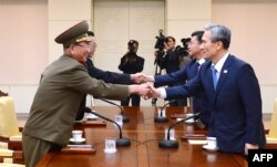 South Korean National Security Director Kim Kwan-jin, right, and Unification Minister Hong Yong-pyo, second from right, shake hands with Hwang Pyong So, left, top political officer for North Korea'ss Army, and Kim Yang Gon, a senior North Korean official responsible for South Korean affairs, during a meeting in Paju, South Korea, Aug. 22, 2015.
